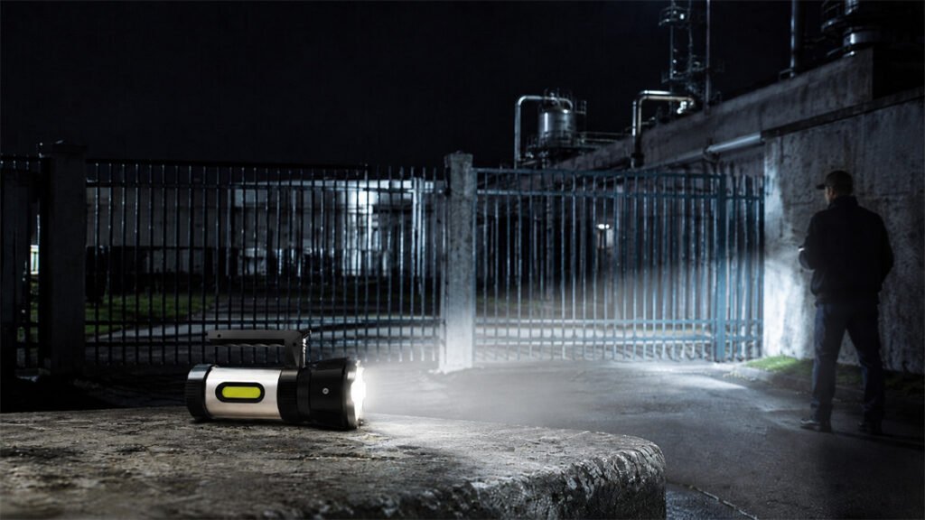 A rechargeable searchlight uses cool white light during an outdoor night inspection.